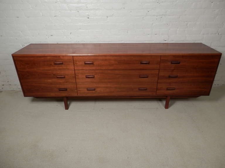 Unusual Danish nine drawer dresser with offset rosewood pulls. Extra long size. Great teak grain and vintage modern lines.rnrn(Please confirm item location - NY or NJ - with dealer)