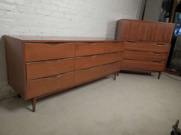 Matching pair of mid-century modern dressers by American of Martinsville feature striking walnut grain, with complimentary brass trim. Offering spacious nine-drawer low dresser and matched highboy dresser, this set is perfect for any bedroom