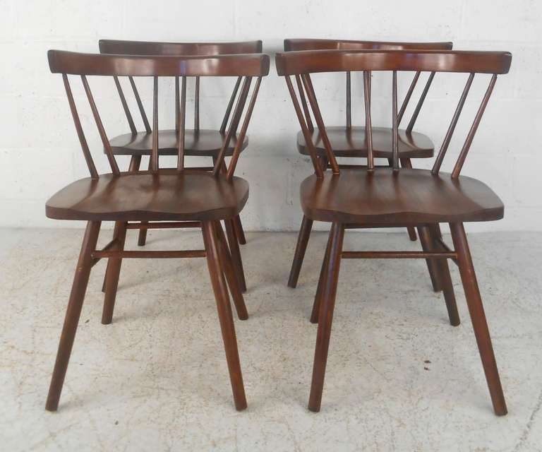 Set of four mid-century walnut chairs with spindle backs and tapered legs. Please confirm item location (NY or NJ).