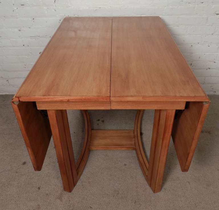 Outstanding drop-leaf dining table with three leaves! Designed by T.H. Robsjohn-Gibbings for Widdicomb and sold in the John Stuart store, this table goes from a quaint folded table to extending over 100 feet! Well designed with curved legs that