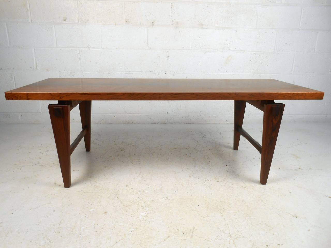 This beautiful vintage rosewood coffee table boasts a lovely rosewood veneer, tapered legs, and quality stretchers for added stability and detail. Please confirm item location (NY or NJ).