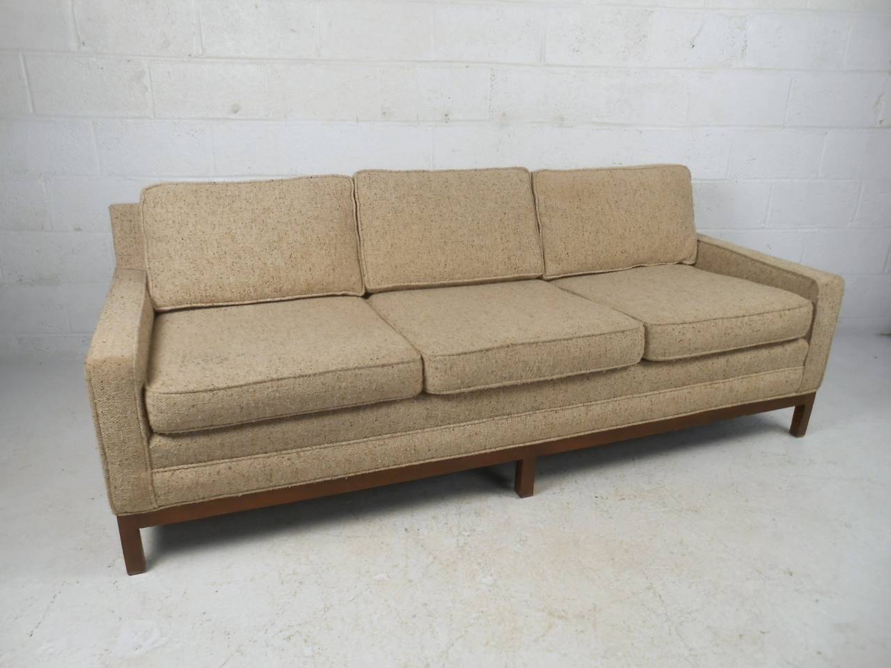 This beautiful three-seat sofa features a unique walnut base, vintage fabric, and comfortable upholstery. Unique Florence Knoll style is showcased with the vintage fabric, clean modern lines, and walnut hardwood base. Matching love seat also