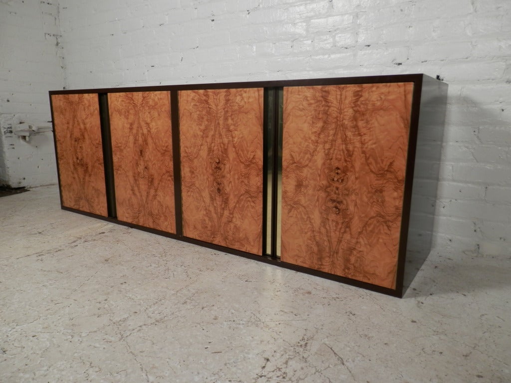 Stunning Milo Baughman style floating wall credenza with outstanding burl wood doors, and brass trim. Adjustable shelves and sliding drawer inside.