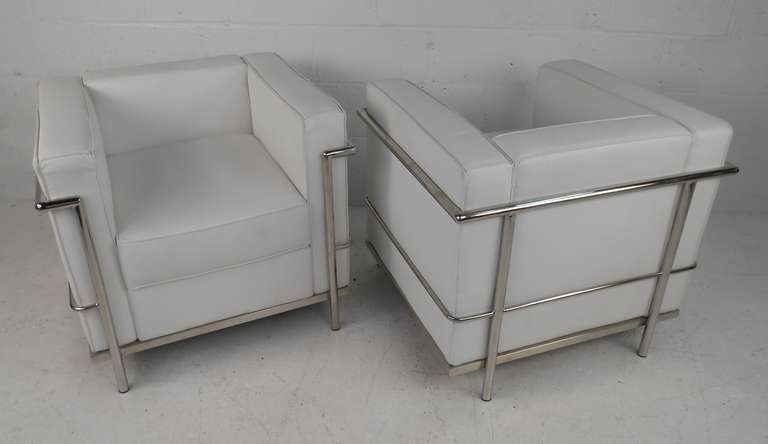 This stylish pair of Mid-Century style white leatherette and tubular chrome frame lounge chairs make a comfortable addition to any seating area. Unique le Corbusier style makes these plush club chairs an impressive addition to any living room or