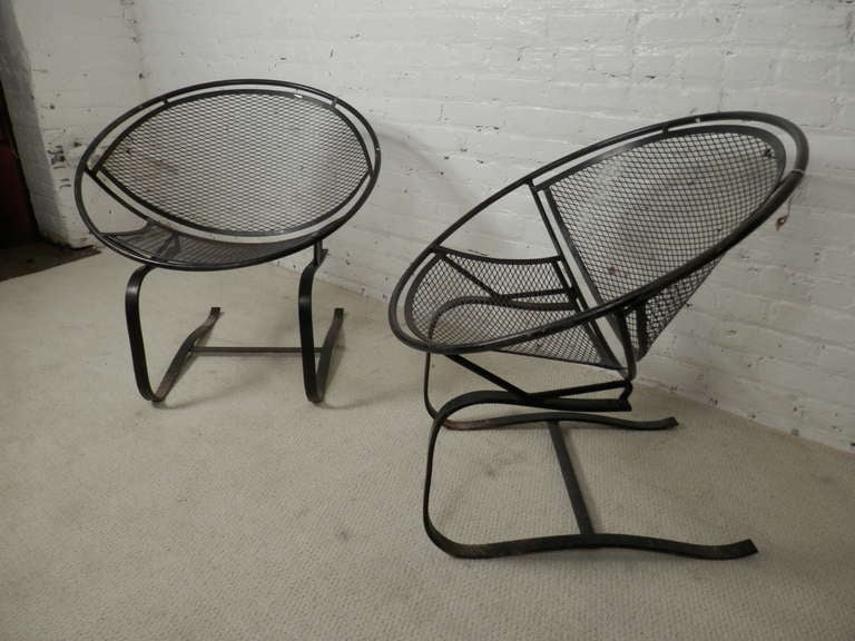 Pair of vintage modern designer patio chairs by Maurizio Tempestini. Iron clamshell style shape are very distinctive and desired. The cantilevered spring legs allow a gentle rock or bounce while seated.

(Please confirm item location - NY or NJ -
