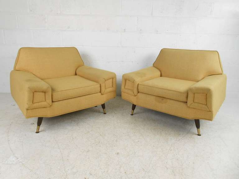 This stylish pair of mid-century modern American lounge chairs feature a unique sculptural modern design, with wide arms, tapered legs, and brass sabots. Please confirm items location (NY or NJ).