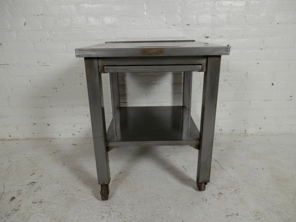 Handsome bare metal side table with sliding shelf.