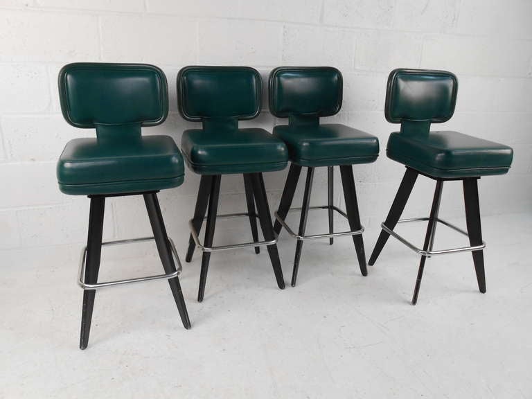 Four vintage stools upholstered in heavy grade vinyl with swivel seats and memory return. Stainless footrest with black painted aluminum legs. Well constructed. Others available. Please confirm item location (NY or NJ) with dealer.