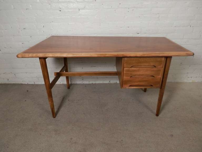 Very unusually shaped writing desk from Denmark featuring a trapezoid shaped top, getting wider on the left side. Well made and nicely detailed with accenting blonde wood trim, inset handles, and tapered legs. Design is similar to the American made