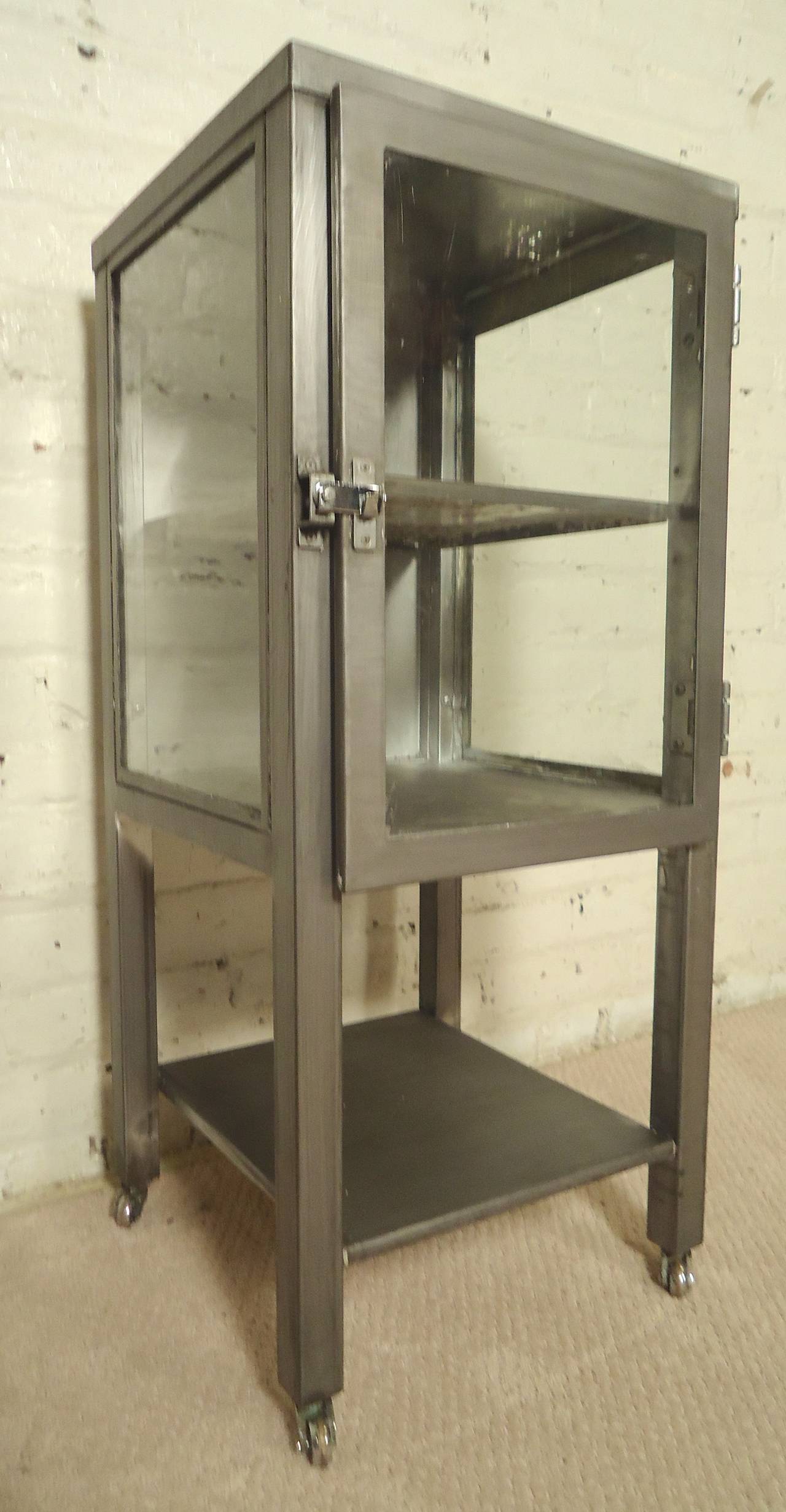 Very unusual side cabinet with glass sides. Refinished in a bare metal style finish and set on casters. Removable metal shelf and bottom shelf. Great as a modern nightstand or bathroom cabinet

(Please confirm item location - NY or NJ - with