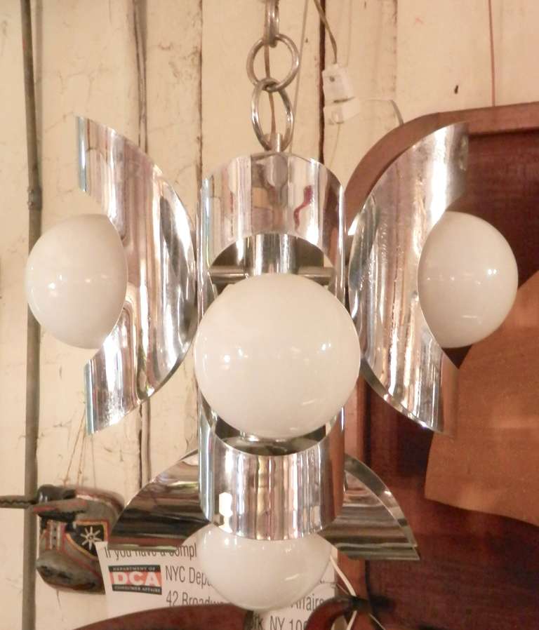 Mid-century five globe chandelier with surrounding bent chrome plates. The white globes give a soft glowing light, with the chrome acting as a reflecting mirror, casting light back into the fixtures center.

(Please confirm item location - NY or