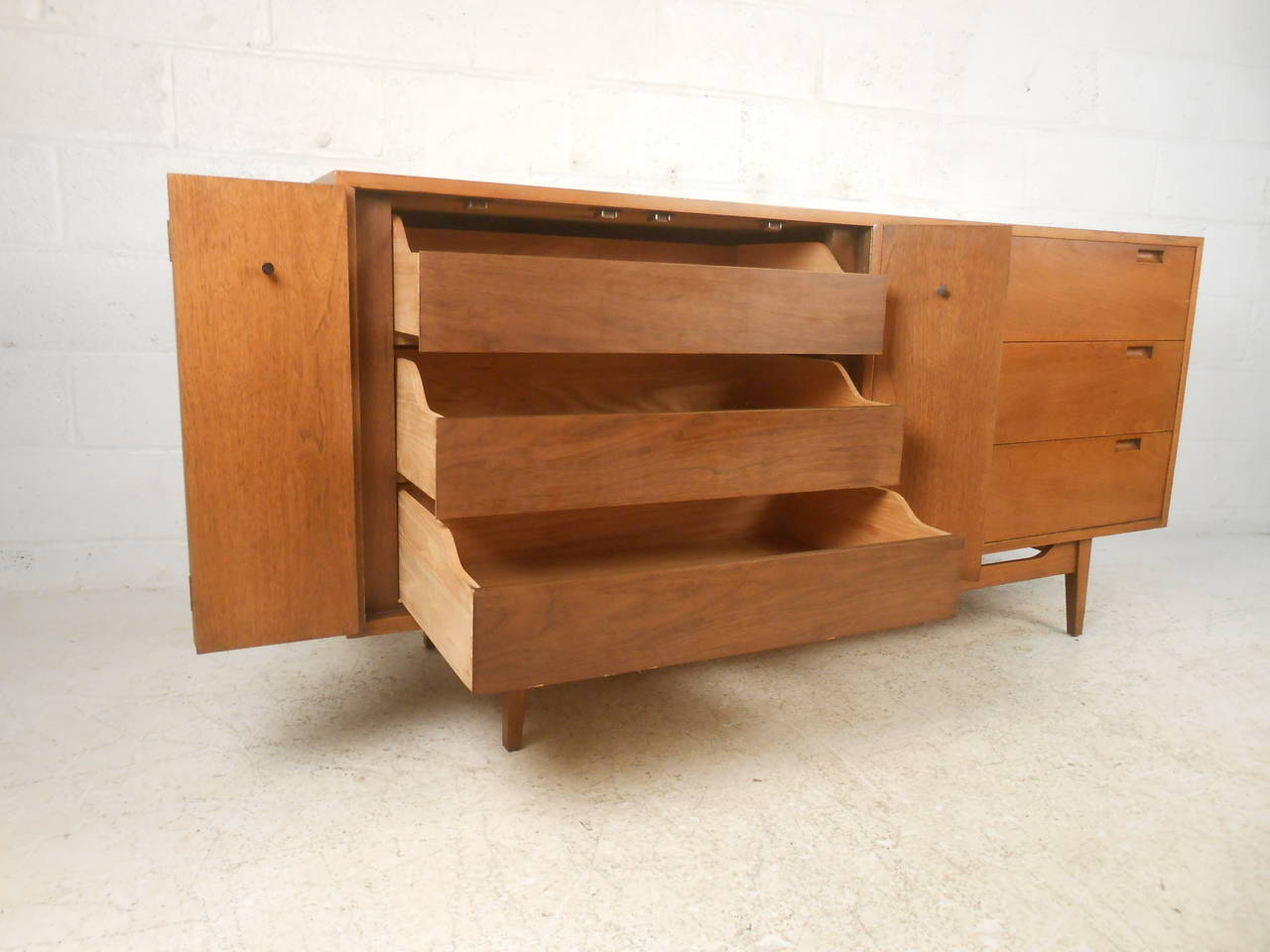 Rare vintage dresser with six drawers made by American Of Martinsville. Walnut grain throughout, tapered legs with sculpted stretcher, carved handles, rosewood cone pulls. Very unusual design with plenty of functionality.

(Please confirm item
