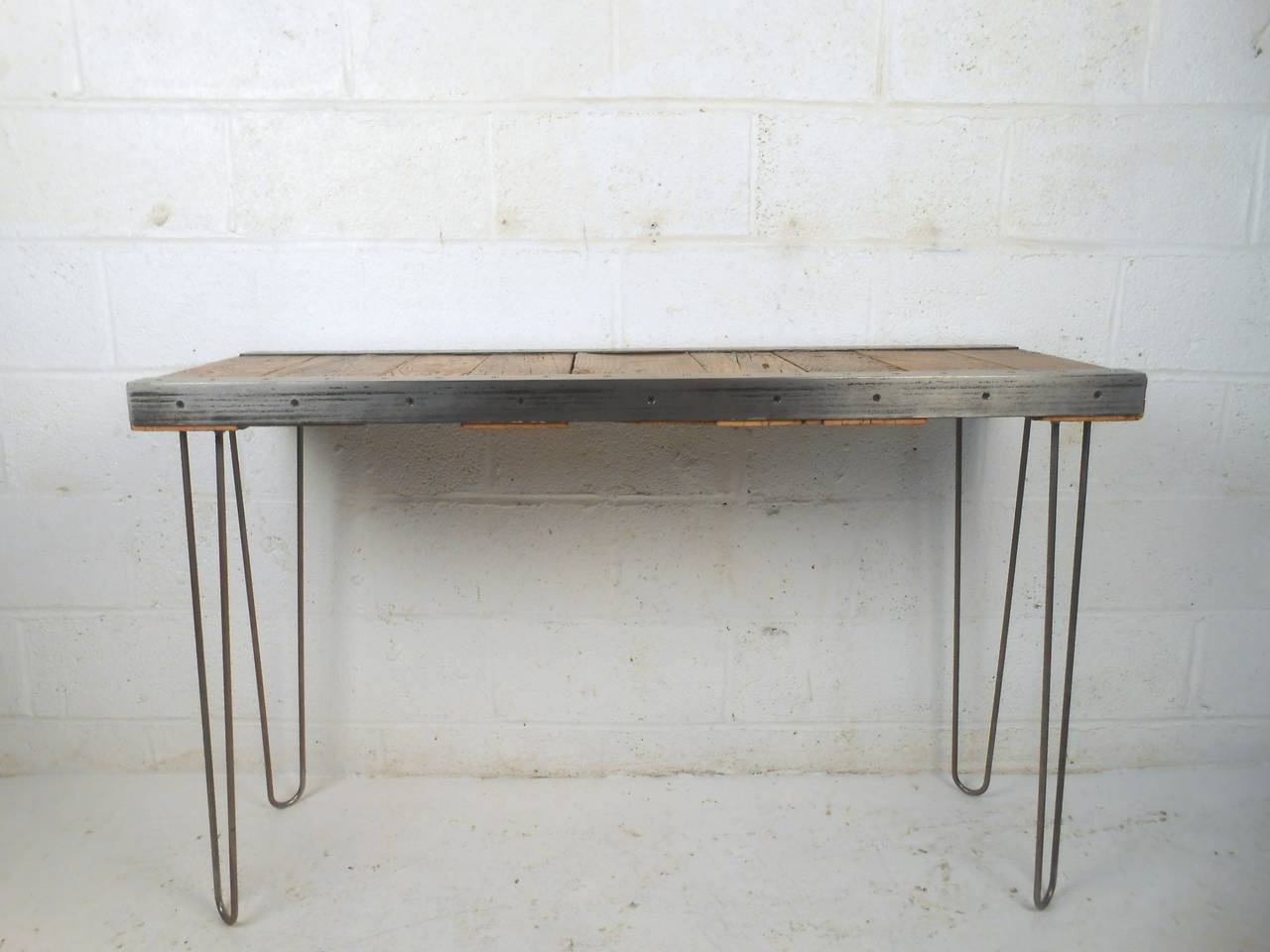 This contemporary Industrial style console table makes a unique entryway table, writing desk, or workstation. Unique brushed metal trim, hairpin legs, and reclaimed wood top make for a great addition to any interior. Please confirm item location (NY