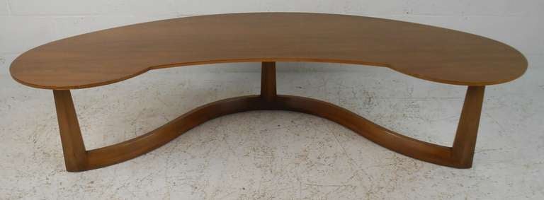 Crescent shaped midcentury coffee table by John Widdicomb with tripod serpentine base and tapered legs. Quality craftsmanship with elegant walnut wood grain throughout. Please confirm item location (NY or NJ) with dealer.

 