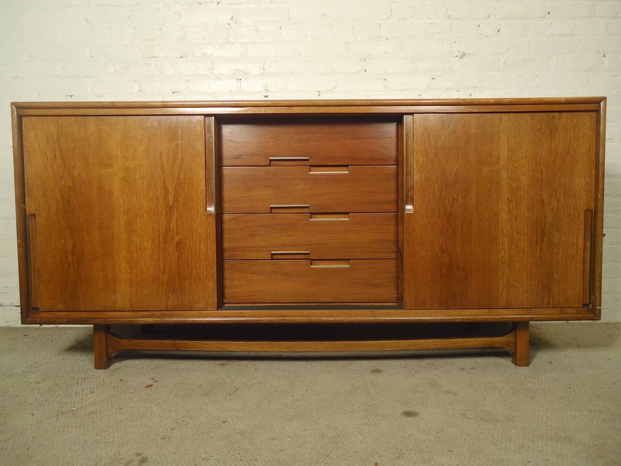 Unusual modern dresser with nine drawers and removable sliding doors. This piece can be a dresser, credenza or sideboard depending how you arrange the doors. Nice brass trim on the inset handles, sculpted stretcher, attractive walnut grain