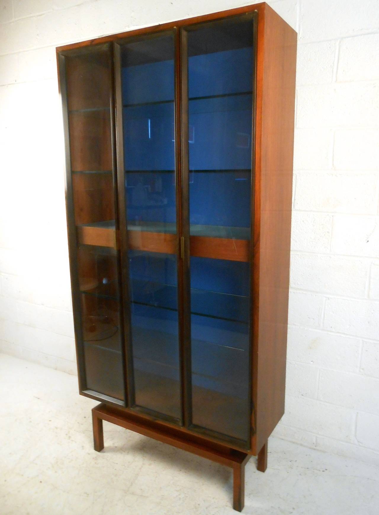 This beautiful custom built display cabinet features six shelves for storage, three doors for access, and back lit display. This impressive and well made piece was a custom creation by Mid-Century designer Samson Berman. Please confirm item location