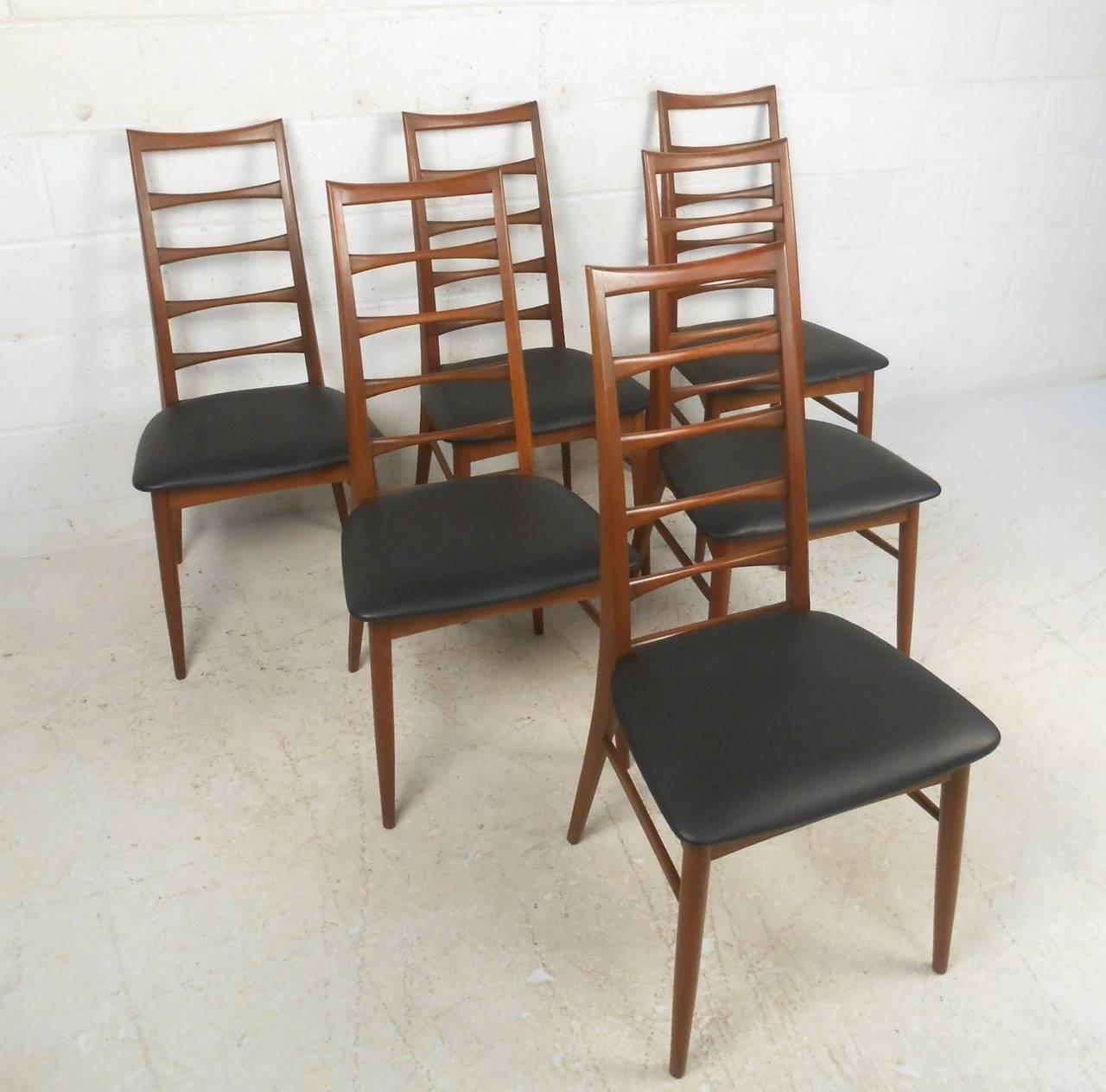 This gorgeous Mid-Century Modern dining set includes six ladder back Kofoed chairs and a wonderful teak draw leaf dining table. Wonderful sculpted backs, added stretchers for support, and tapered legs show off the wonderful design of this Classic
