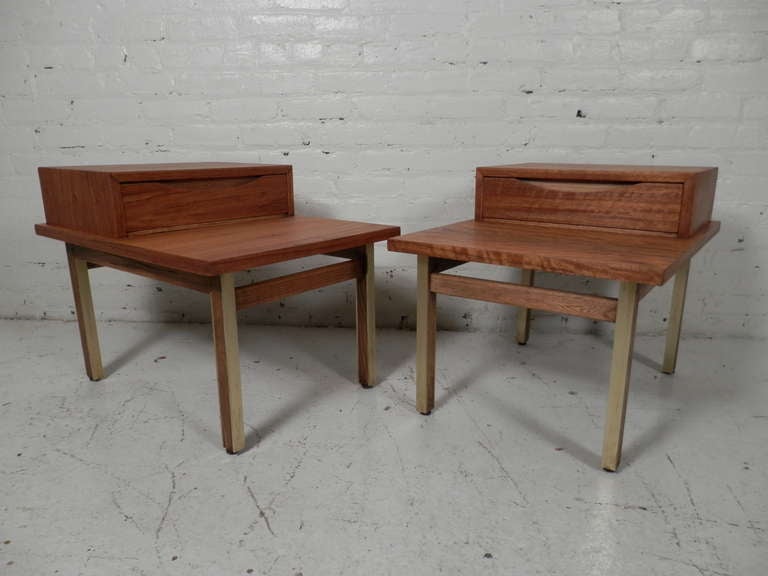 Pair of outstanding bedside tables by American Of Martinsville. Stunning tiger stripe wood grain runs across the body, with brass framed legs, reminiscent of Paul McCobb's style. Nice inset carved handle on the drawer. Bedside or sofa side