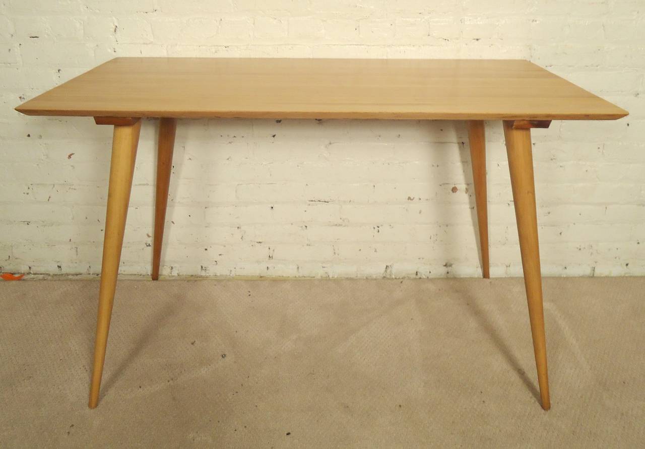 Mid-Century Modern table with long attractive cone legs and straightforward blonde top. Classic McCobb lines and style. Makes for a handsome console table or petite dining table.

(Please confirm item location - NY or NJ - with dealer).