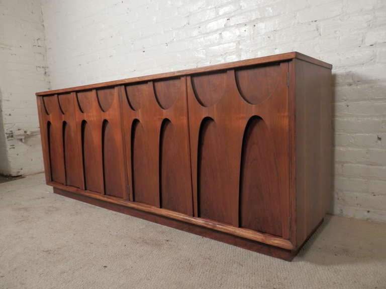 Exquisite handcrafted walnut credenza by Broyhill for their Brasilia series. With integrated front panel handles, left and right double doors that expose three pullout drawers and an extra area to add shelves or use for storage.

(Please confirm