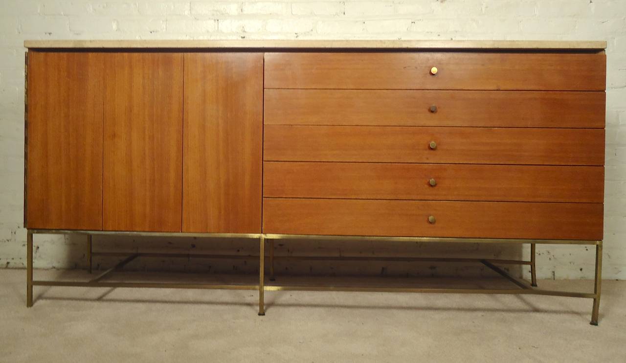 Mid-Century long sideboard designed by Paul McCobb for hi Irwin Collection. Folding door cabinet, five wide drawers, brass hardware throughout and thick marble top. Finished back.

(Please confirm item location - NY or NJ - with dealer).
