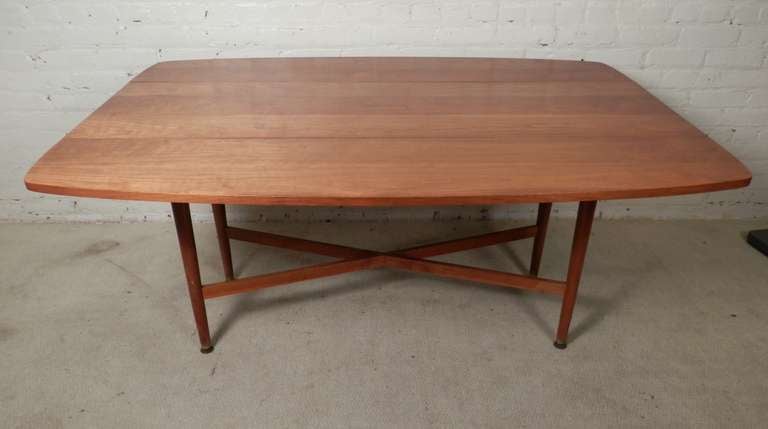 Mid-century modern dinning table made by Drexel for their Declaration line. Fantastic walnut grain, brass capped legs and crisscross stretchers. Leaves are on spring mechanism and are sturdy when extended. Used easily as a console or dinning