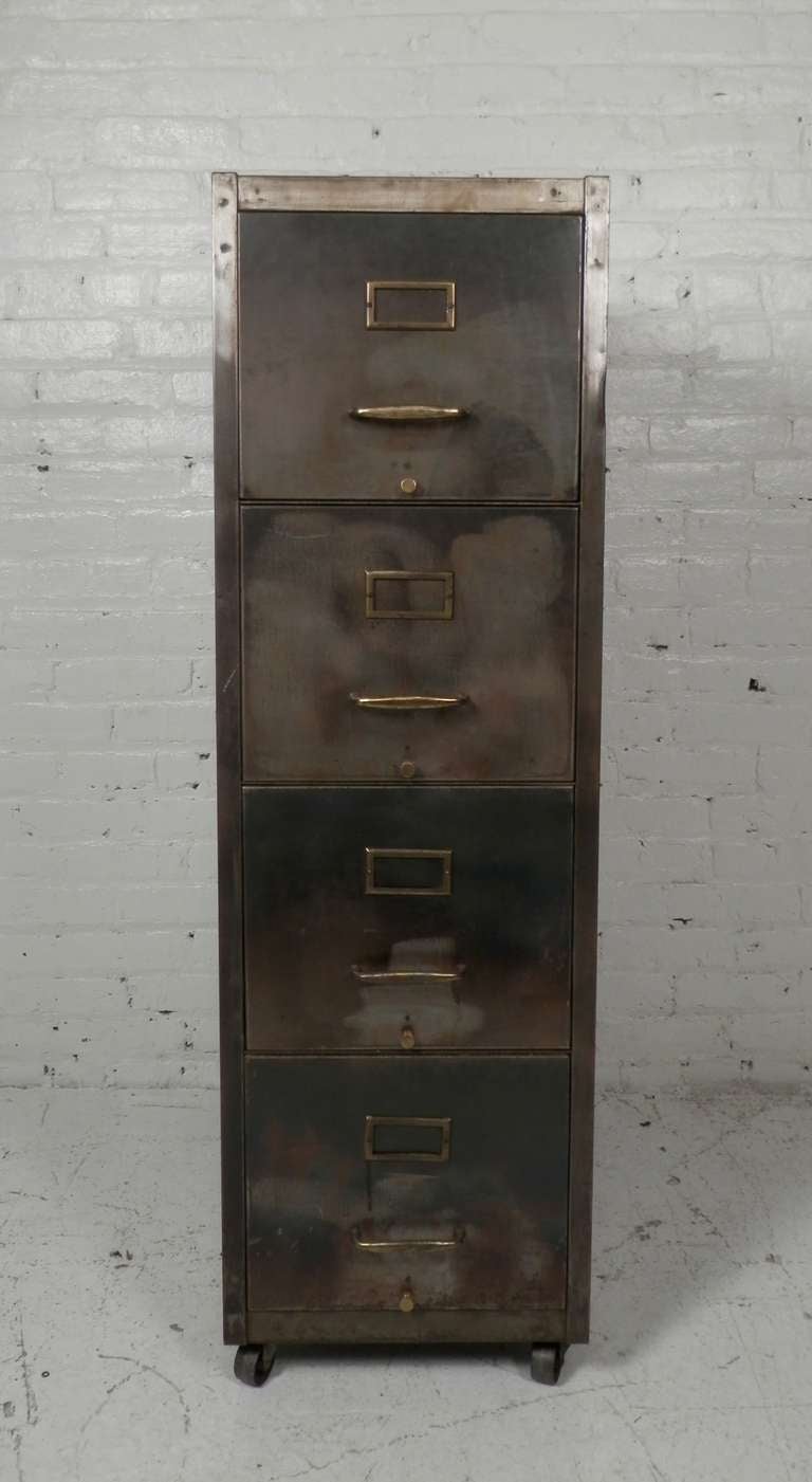 Industrial metal four drawer file cabinet on casters. Brass hardware including tag holders. Newly striped and lacquered for a handsome industrial look.

Drawers measure 12w 25d 9 1/2h.

(Please confirm item location - NY or NJ - with dealer)