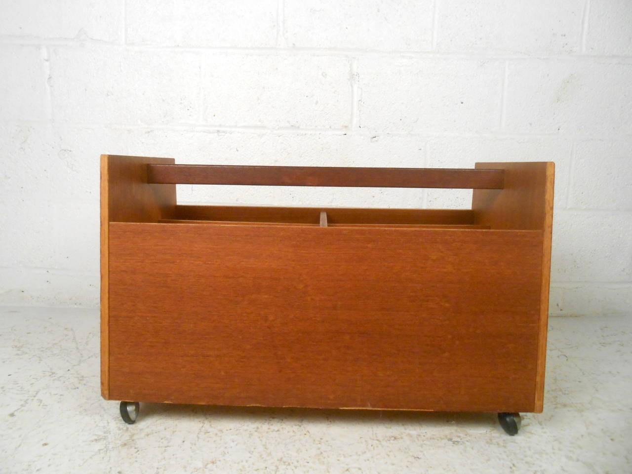 This Mid-Century magazine caddy features a beautiful teak construction, chrome castors, and six storage compartments which offers a modern accent to any home or office space.

Please confirm item location (NY or NJ) with dealer.