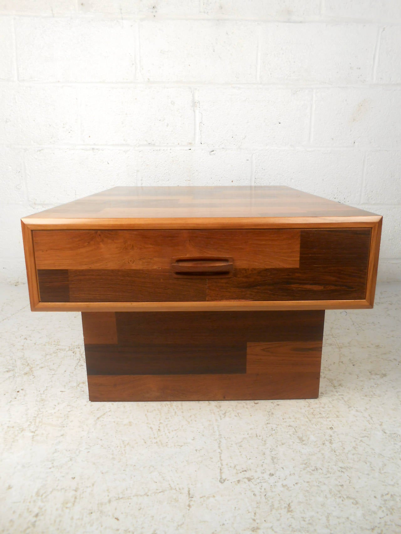 This mid-century modern end table features a unique patchwork finish, single drawer, and carved wood pull, which offers a distinct modern flare to any home or office space.

Please confirm item location (NY or NJ) with dealer.