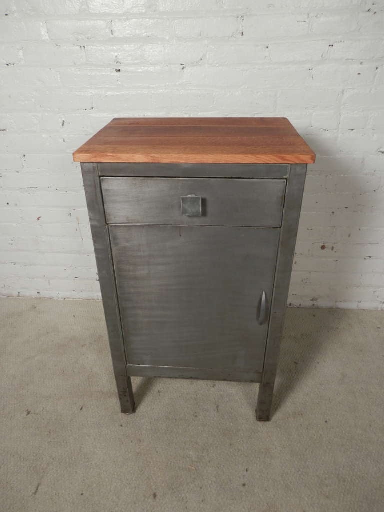 Vintage metal single door cabinet with top drawer by Norman Bel Geddes for Simmons. Newly striped and refinished. Wood top, original label and original square drawer pull. Easily used as a pantry cabinet, nightstand, or hallway stand.

(Please