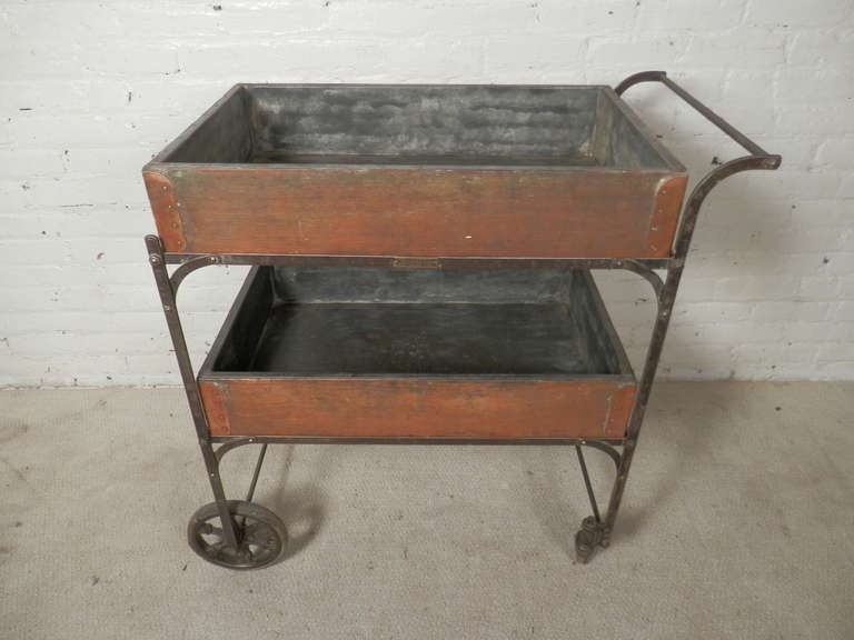 Unusual machine age style cart with two removable wood bins. Large original casters, two of them with 360 degree turning radius for easy moving. Aged copper reinforcements on the bins with galvanized lining. Includes brass manufacturer's plate. A