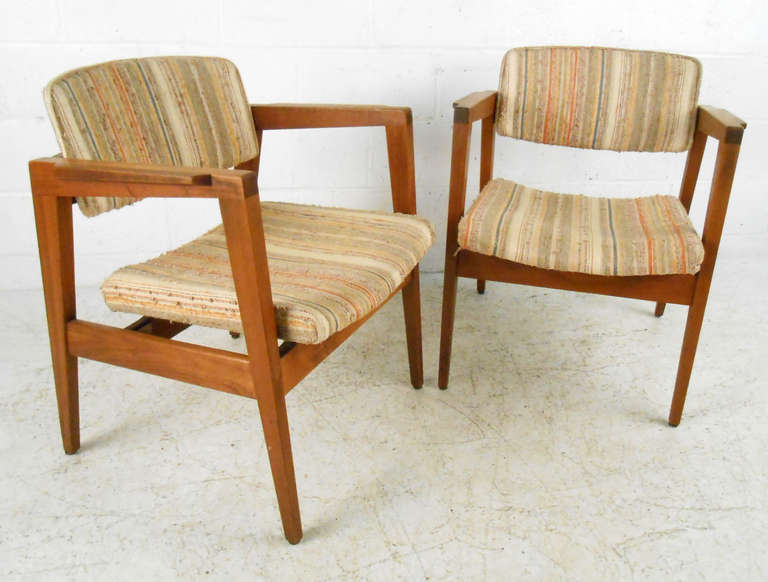This sturdy pair of side chairs feature vintage upholster on sturdy wooden frames. The unique armrests and tapered legs make this matching set a beautiful example of mid-century American design. Original manufacturer's tags still attached. Please