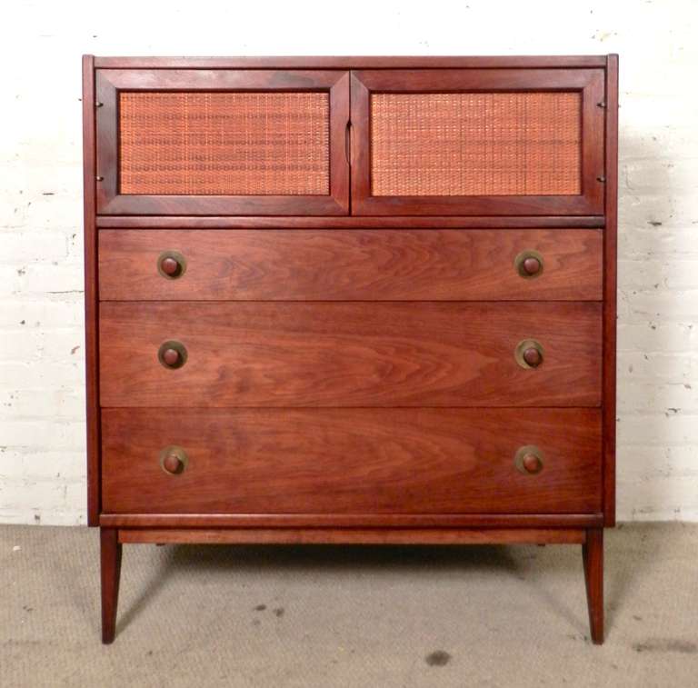 Tall 1960's American made walnut dresser with cane doors and hand carved handles. Features three wide drawers and tapered legs. A handsome gentleman's chest.

(Please confirm item location - NY or NJ - with dealer)