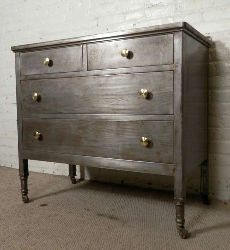 Four drawer metal dresser with accenting brass hardware. Produced by H. D. Dougherty & Co., Philadelphia, PA. Features rolling casters and wide drawers, and a sleek modern industrial finish.

(Please confirm item location - NY or NJ - with dealer)