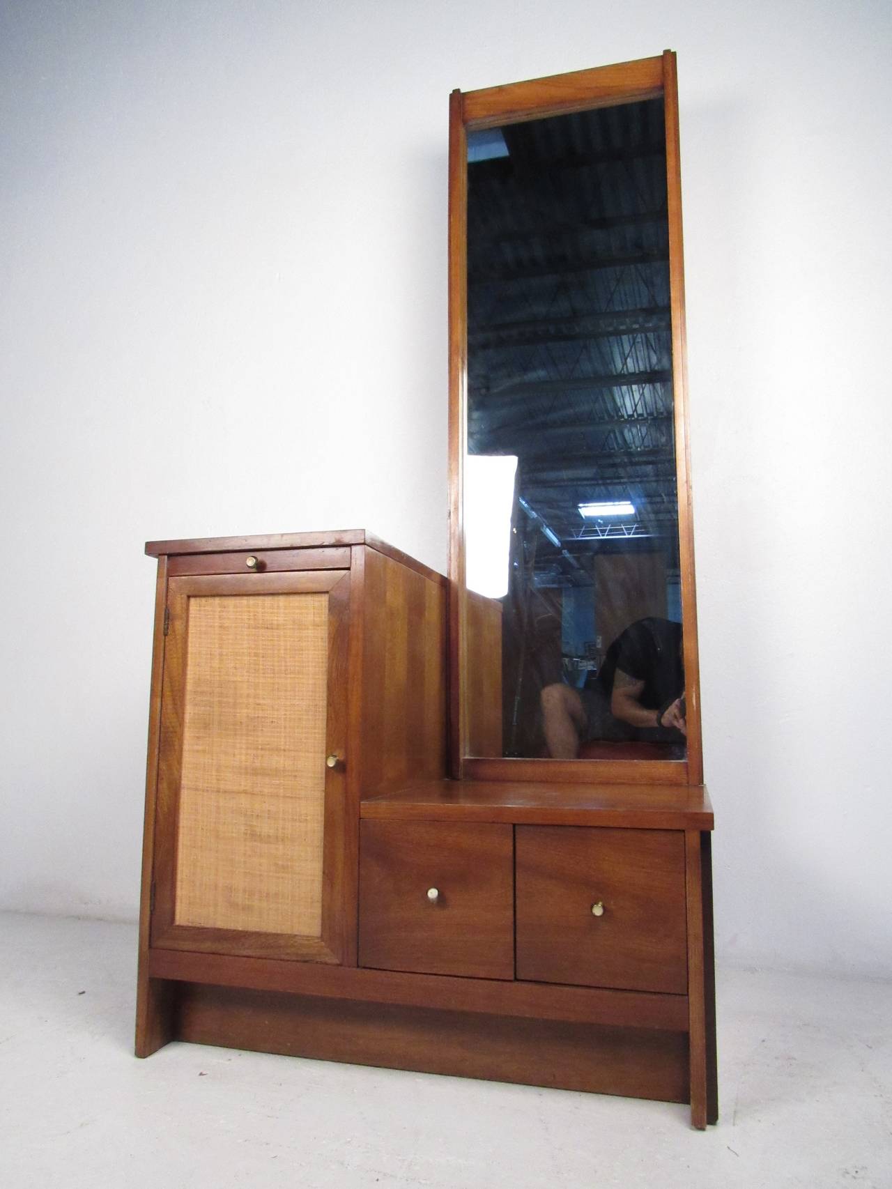 This Mid-Century cabinet features a beautiful walnut finish, cane front, tall mirror, pull-out surface with white finish, and two drawers with unique pulls which offer a modern flare to any home or office space.

Please confirm item location (NY