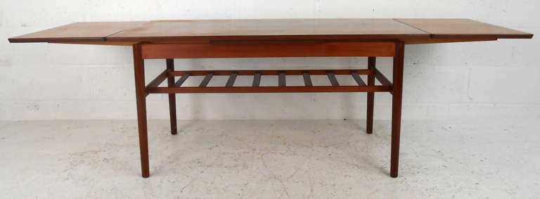 This Danish teak coffee-table features unique extendable draw leaves (open length 73 Inch). With beautifully designed lines and useful second shelf, this table makes a beautiful addition to any midcentury home. Please confirm item location (NY or