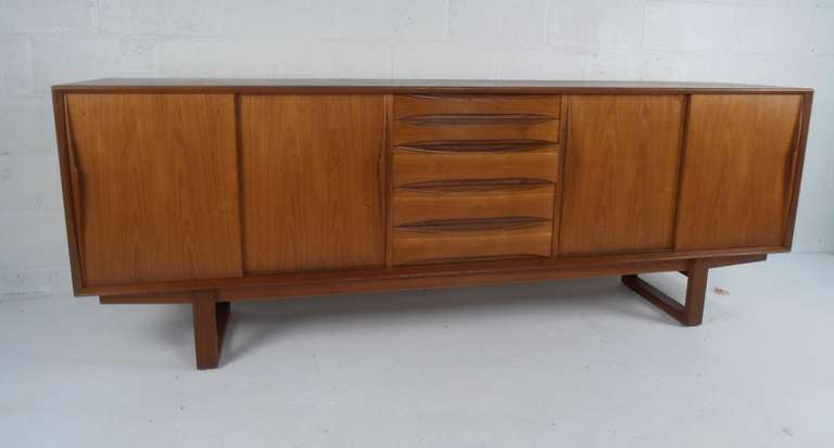 This stunning sled leg teak server by Arne Vodder for Sibast features five center drawers and sliding doors enclosing adjustable shelves. Ideal buffet sideboard for dining room or for office/television storage. Please confirm item location (NY or