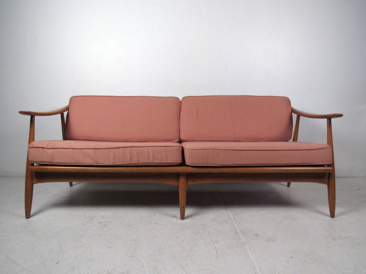 This Mid-Century Modern sofa features a vintage walnut frame with sculpted armrests and vintage upholstery cushions. A unique piece for home or office lounge area, please confirm item location (NY or NJ).