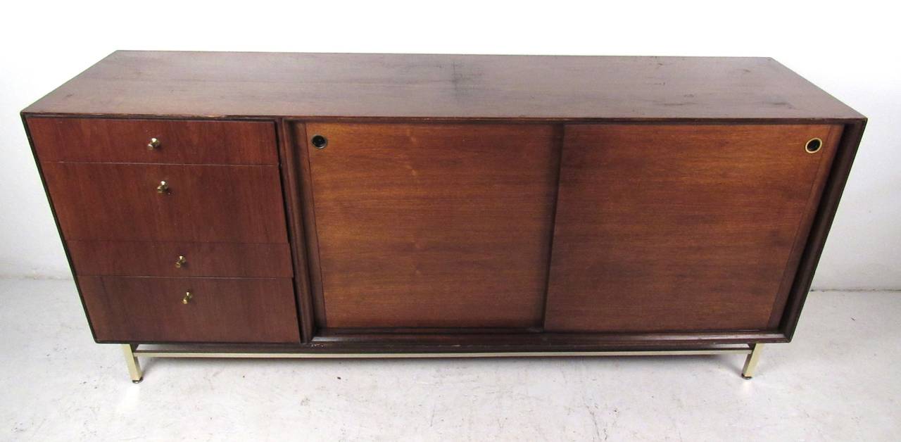 This elegant twelve drawer dresser boasts iconic design by John Stuart in a rich natural walnut. Brass stretcher and unique drawer pulls add to the mid-century appeal of this American made dresser. Wonderful array of drawers for storage in any