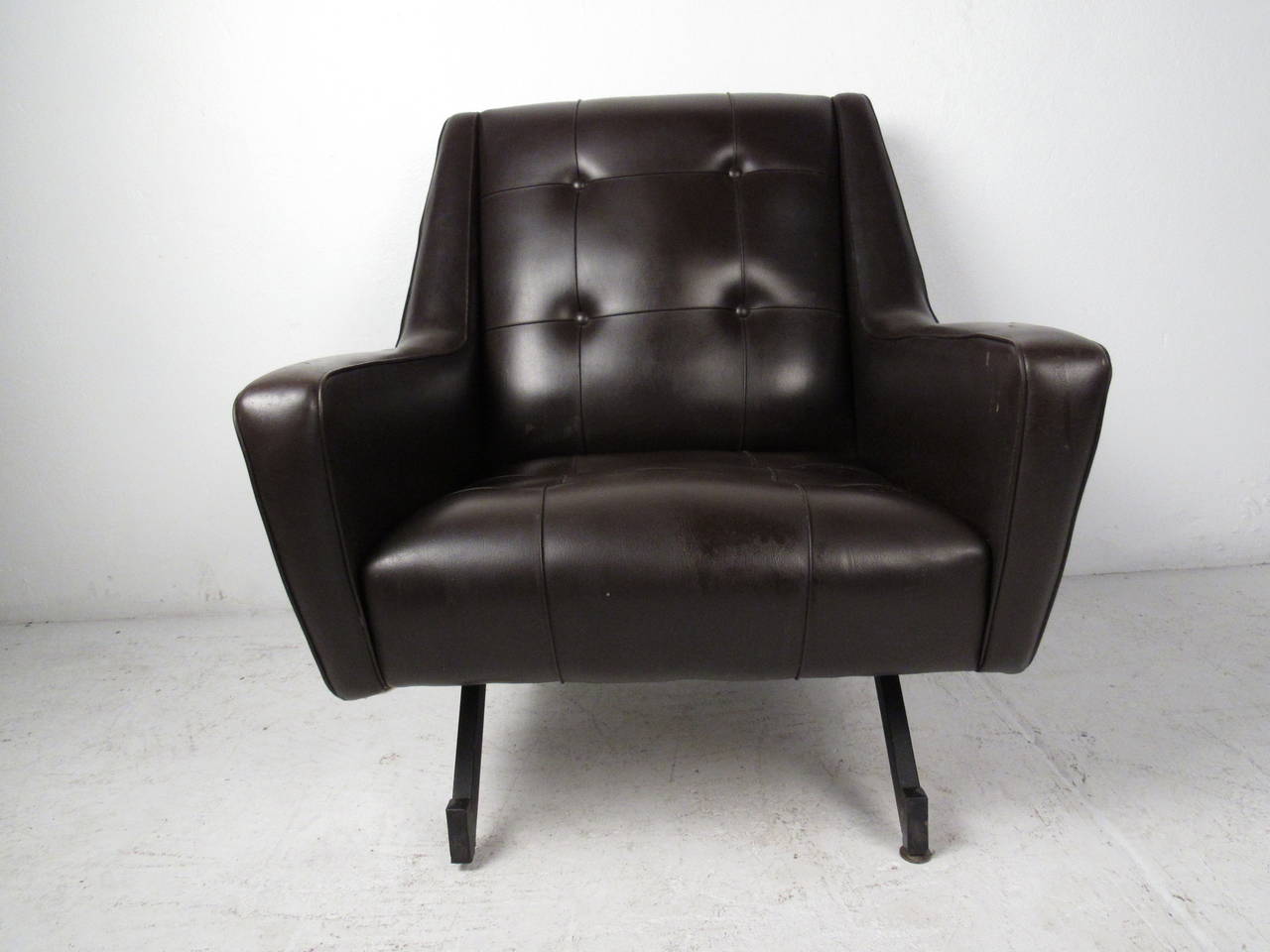 This midcentury lounge chair features chocolate brown tufted vinyl and iron legs which offer comfortable seating and a modern accent to any home or office space.

Please confirm item location (NY or NJ) with dealer.