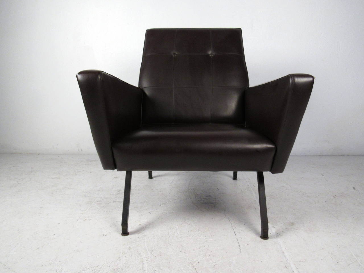 This midcentury lounge chair features sculpted arm rests, iron legs, and a tufted vinyl seat back which offers a modern style and comfortable seating to any home or office space.

Please confirm item location (NY or NJ) with dealer.