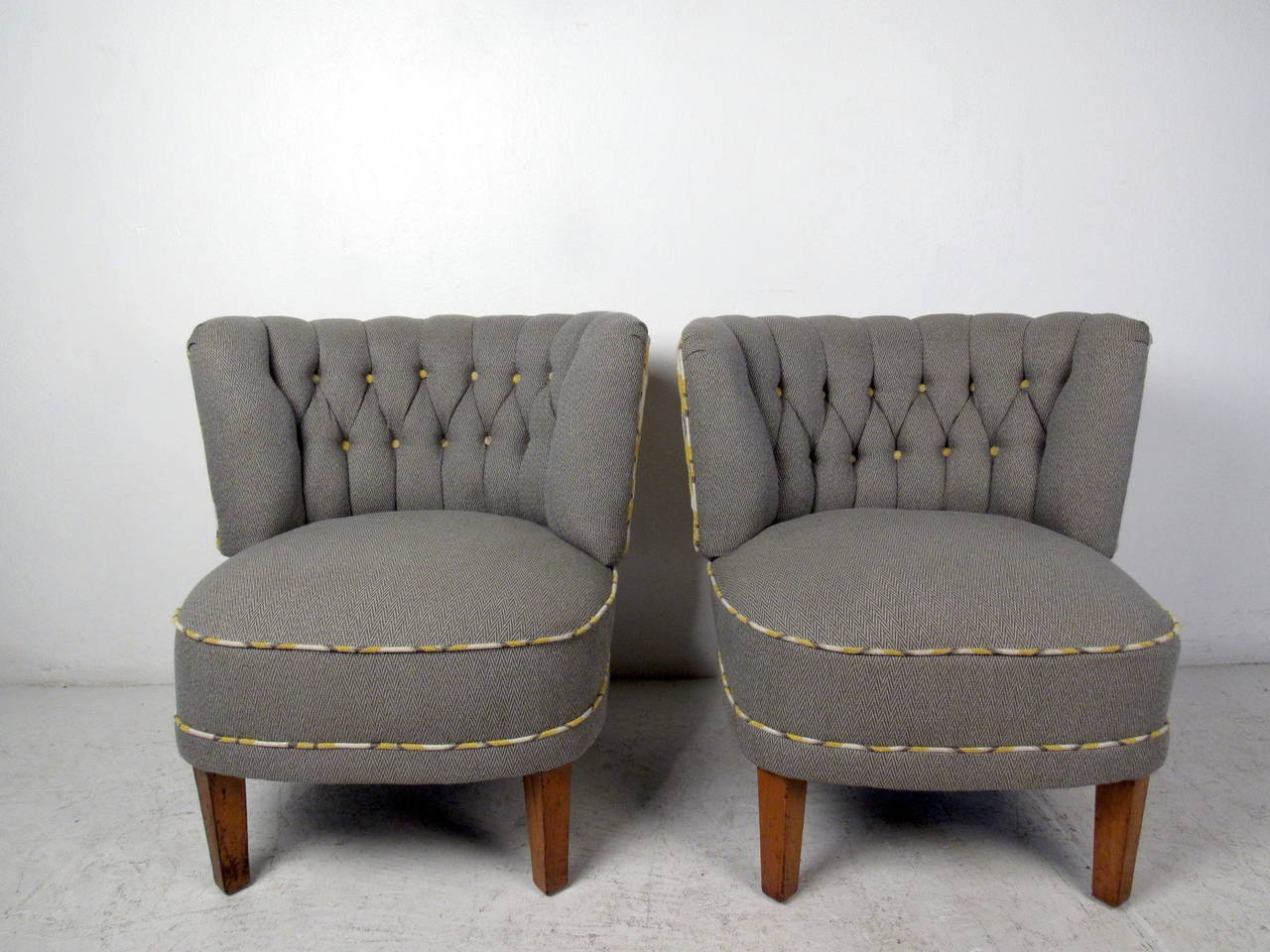 This pair of midcentury style slipper chairs feature a brilliant new upholstery, tufted back, and tapered legs which offer comfortable seating and a bold modern accent to any home or office space. 
 
Please confirm item location (NY or NJ) with