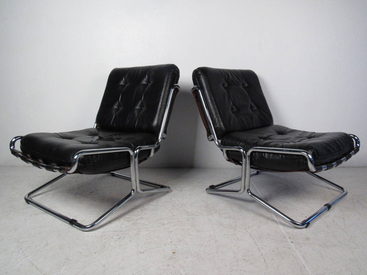 This pair of midcentury Italian lounge chairs features a chrome base, leather strap supports, and comfortable leather upholstery which offers a modern flare and comfortable seating to any home or office space.

Please confirm item location (NY or