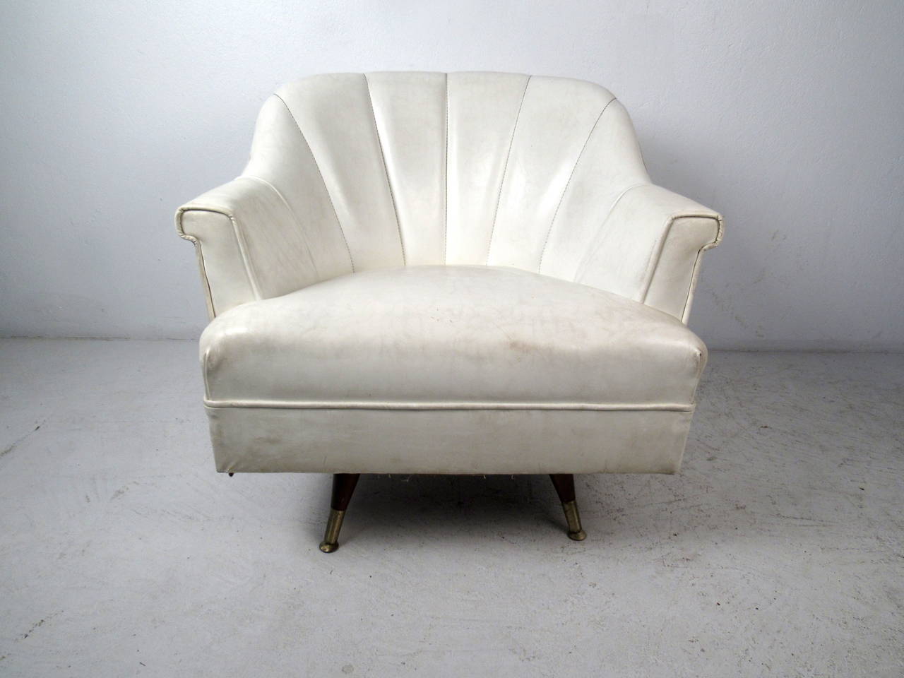 Ce fauteuil de salon de style midcentury est doté d'un siège en vinyle à dossier festonné blanc et d'une base pivotante sur des pieds effilés qui offrent un accent moderne et un siège confortable à toute maison ou espace de bureau.

Veuillez