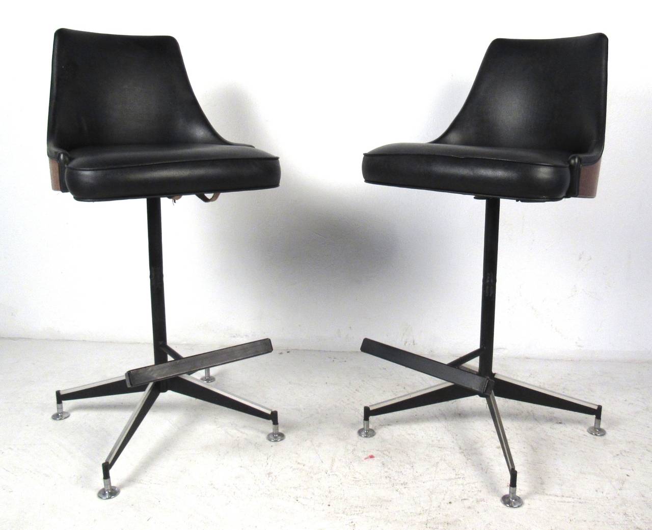 Great pair of mid century swiveling bar stools with black vinyl upholstery and bent wood walnut backs. Please confirm item location (NY or NJ) with dealer.