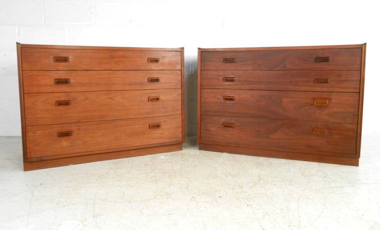This pair of vintage American walnut dressers by Founders Furniture make a stylish storage option for any room. With carved drawer pulls, and unique edge trim this matching pair is a fantastic reminder of the high caliber construction midcentury