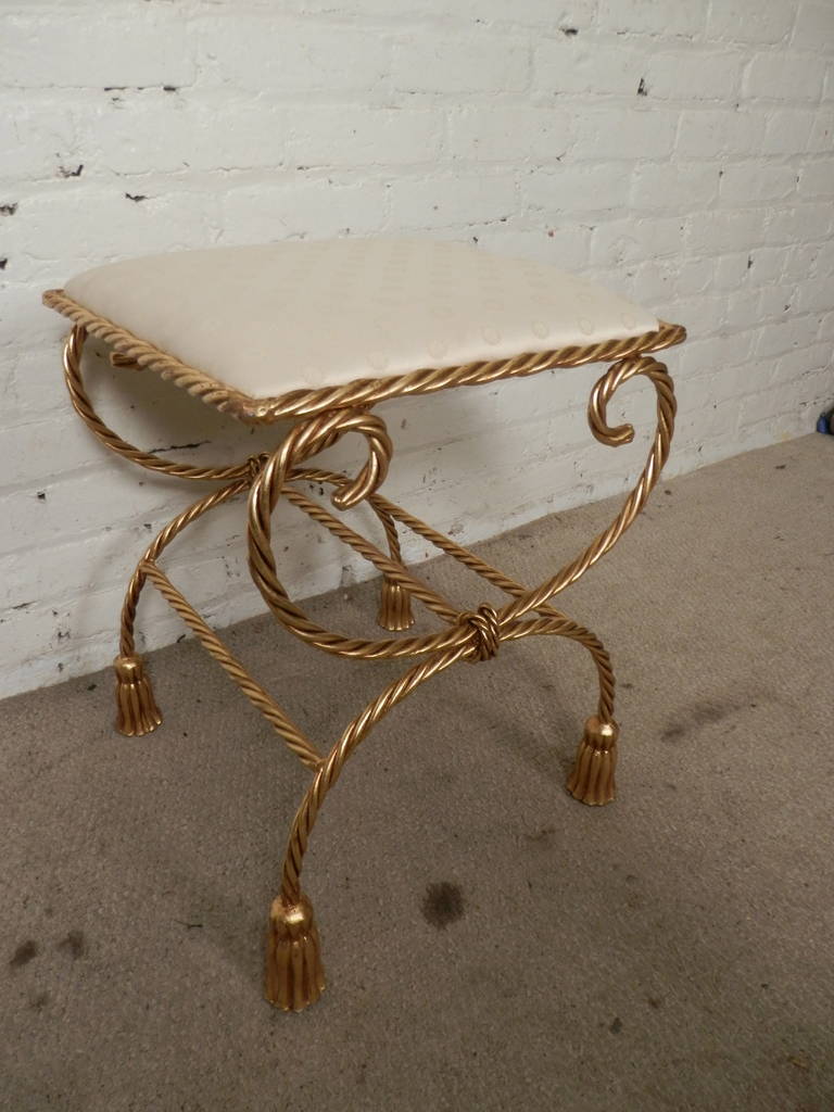 Hollywood Regency style Mid-Century Ottoman with beautifully sculpted twisted brass legs and tasseled feet. Comfortable cloth cushion with spotted design.

(Please confirm item location - NY or NJ - with dealer)