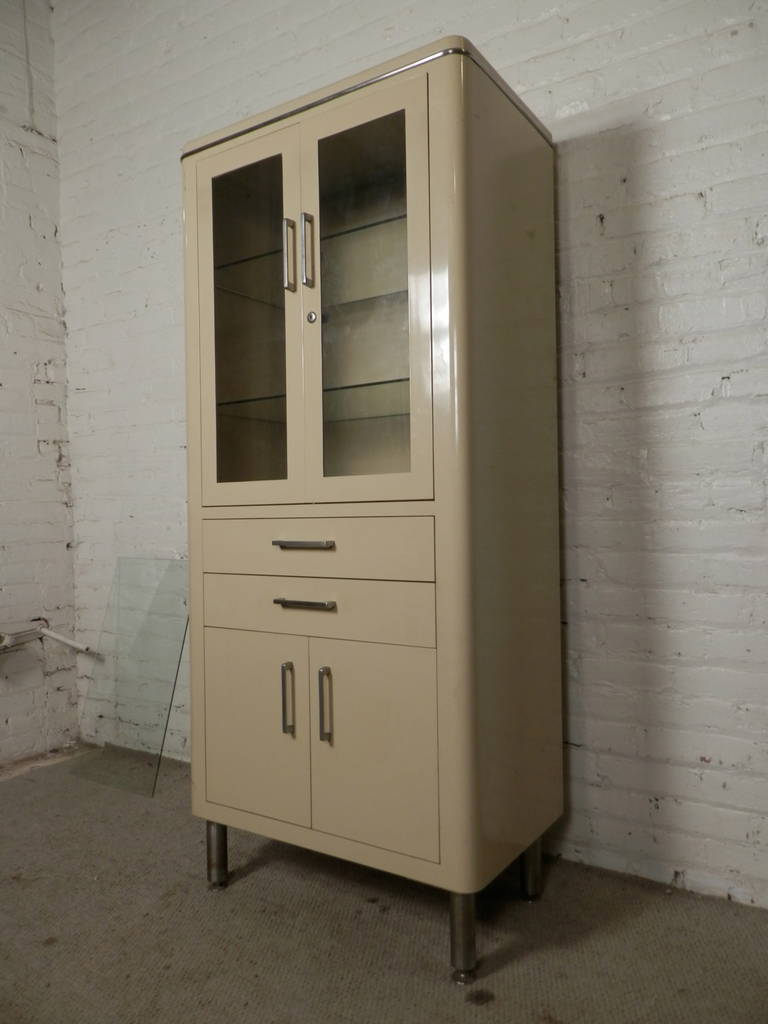 Tall industrial era Henry Hamilton medical cabinet with original paint. Comes with one large cabinet with glass doors and shelves two drawers and one lower cabinet with metal doors. Great for home or office use.

(Please confirm item location - NY