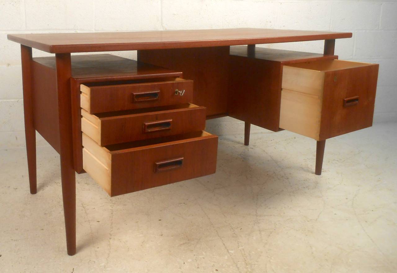 Floating top teak desk with back storage, sculpted handles, tapered legs. Great construction and design with dovetail joints, two locking drawers and usable finished back.

(Please confirm item location - NY or NJ - with dealer).