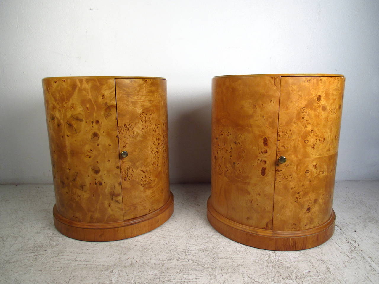 This pair of mid century end tables feature a beautiful burlwood finish, large cabinets with a shelf, brass pulls and a unique round design which offers a bold modern accent and ample storage space to any home or office space.

Please confirm item